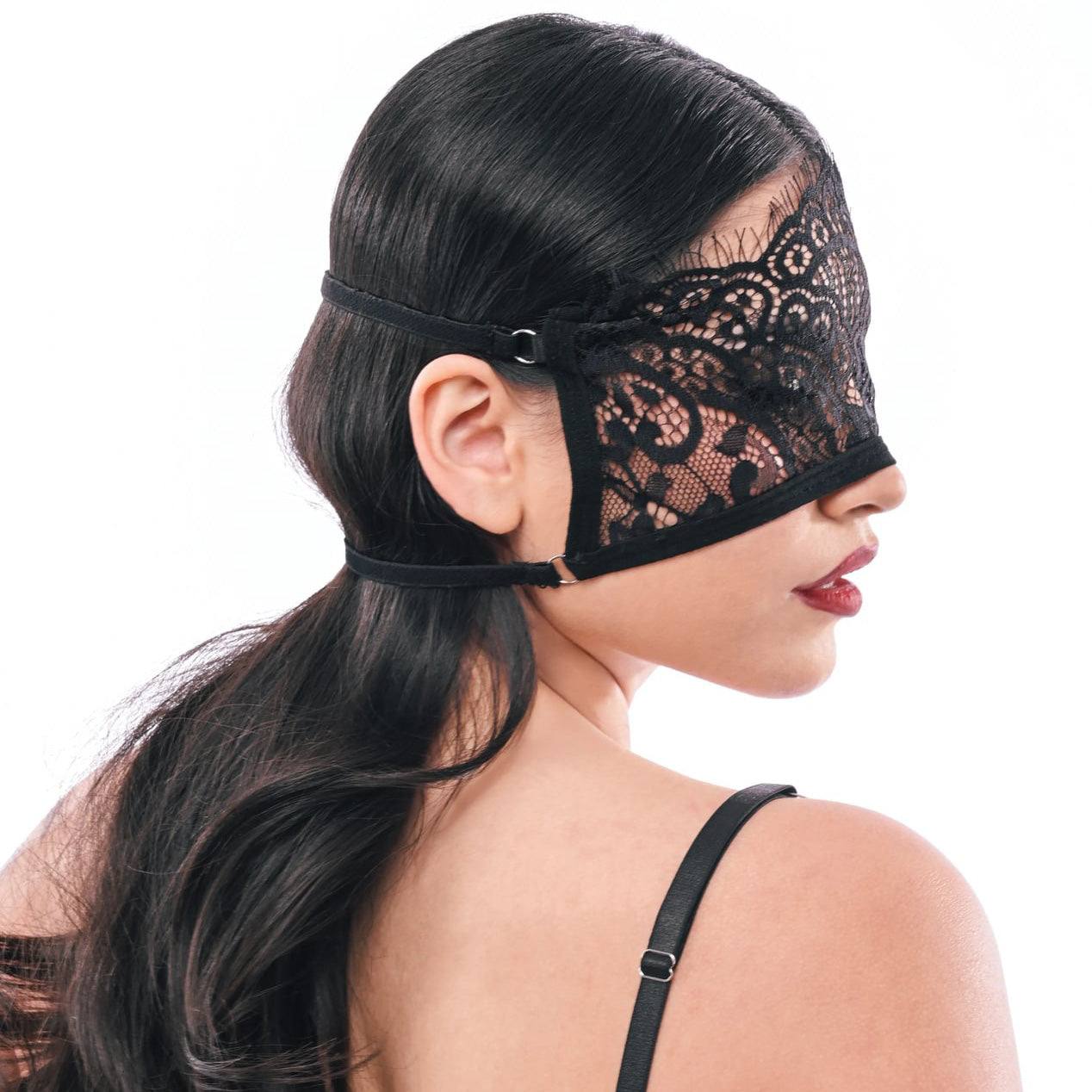 Woman wearing a black lace blindfold on a white background