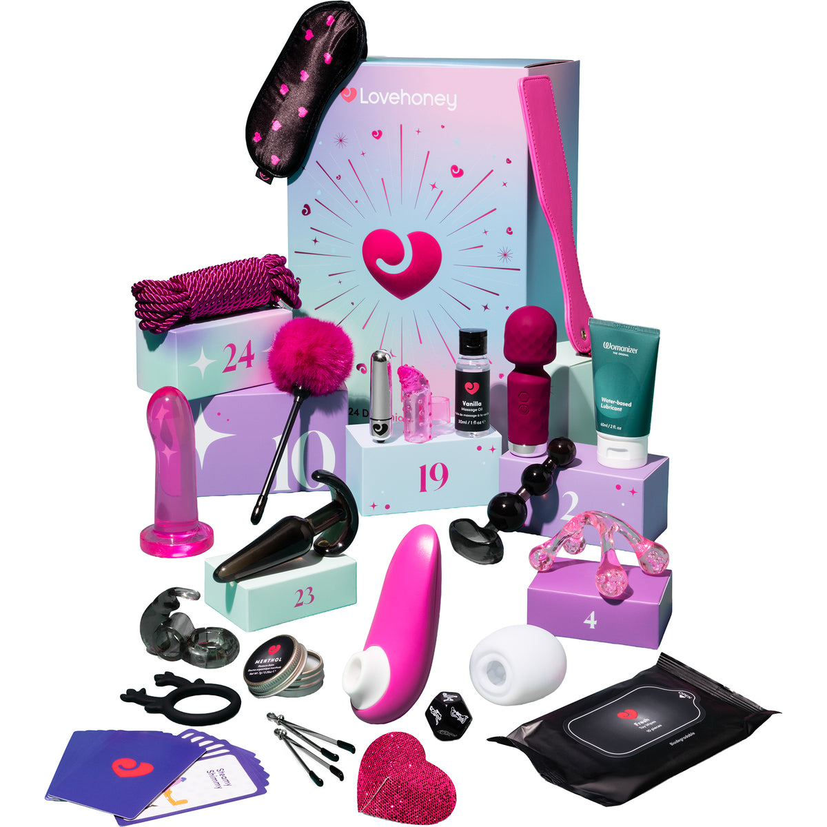 A Lovehoney branded adult wellness gift set arranged in front of a pastel gift box on a white background. The set includes multiple pink and black intimate accessories, small bottles, a tube, a pink fuzzy item, clear and black curved pieces, a black pouch, and small cards.