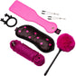 A pink and black adult novelty kit laid out on a white background, including a bright pink strap, a black satin blindfold with pink hearts, a coiled magenta rope, a fluffy hot pink pom-pom stick, three metal pins, and a black reindeer-shaped ring.