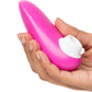 A hand holding a bright pink personal massager with a white control button, shown against a plain white background.