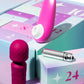 Two intimate wellness devices displayed with a pastel advent calendar box: a bright pink curved wand-style device and a darker magenta textured handheld device, alongside a silver capsule-like item on a branded box marked 24.