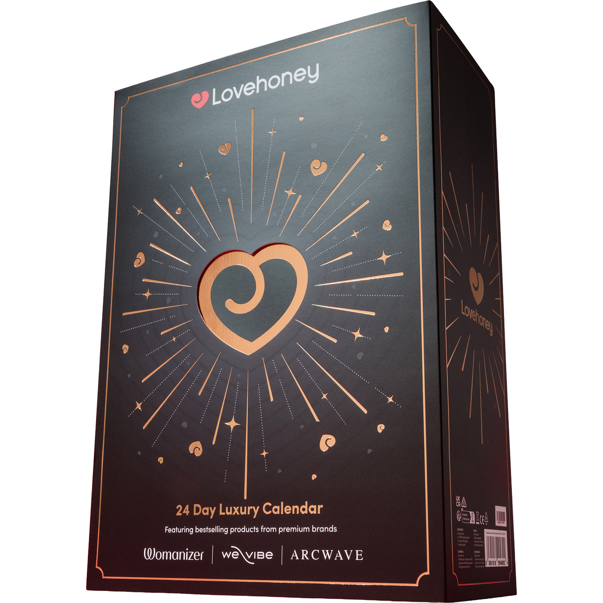A tall rectangular product box for a 24 Day Luxury Calendar by Lovehoney, shown at a three-quarter angle on a plain white background. The box is black with metallic rose gold accents, including a large heart-shaped cutout in the center, radiating lines, stars, and small heart motifs.