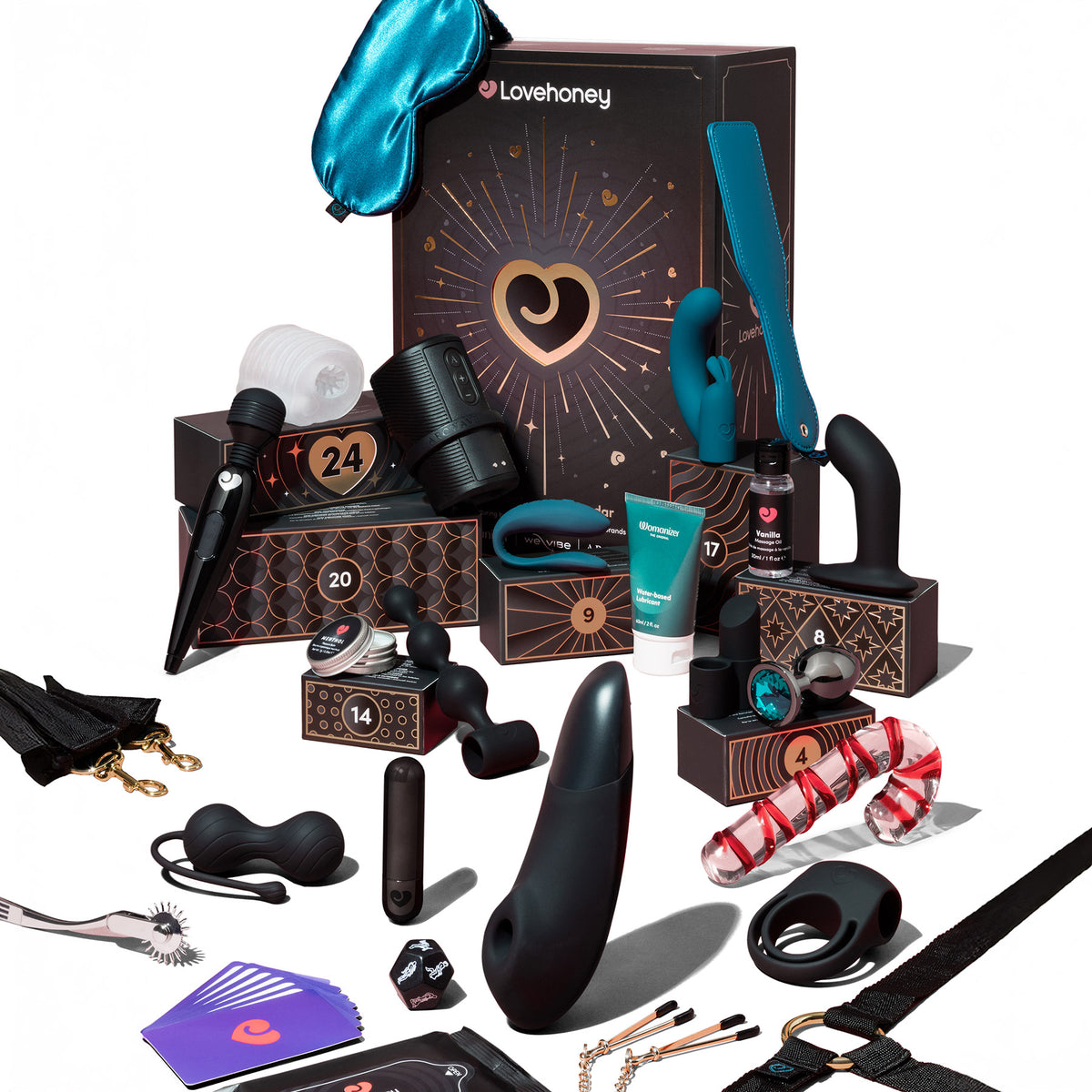 A Lovehoney adult novelty gift set arranged on a white background, featuring multiple black and dark brown boxes with gold details, a bright blue satin sleep mask, black personal massagers, a red-and-white striped dildo, a purple card deck, and other small accessories.