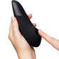 A black silicone personal massager held in a hand, with a finger pressing a button on the side, against a plain white background.
