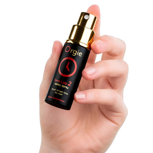 Hand holding a bottle of Orgie Time Lag 2 delay spray against a white background