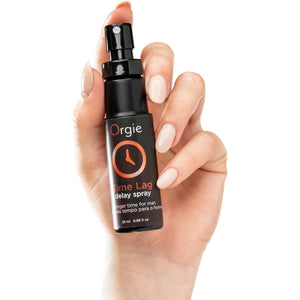 Hand holding a bottle of Orgie Time Lag delay spray against a white background