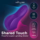 Purple We-Vibe shared couple's grinding vibrator shown on a dark gradient background with blue and pink waveforms, alongside feature callouts including free app, rumbling vibrations, double stimulation, and use on penis and clitoris.