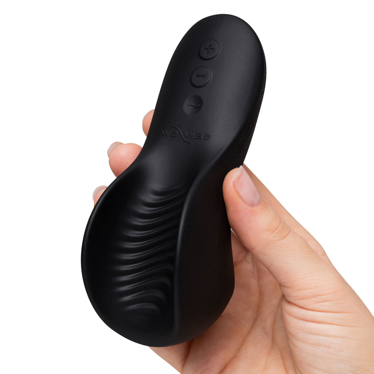 A hand holding a black personal massager against a plain white background. The device has a curved ergonomic shape with textured grooves and three control buttons on the back, with the brand name 'We-Vibe' debossed on the side.
